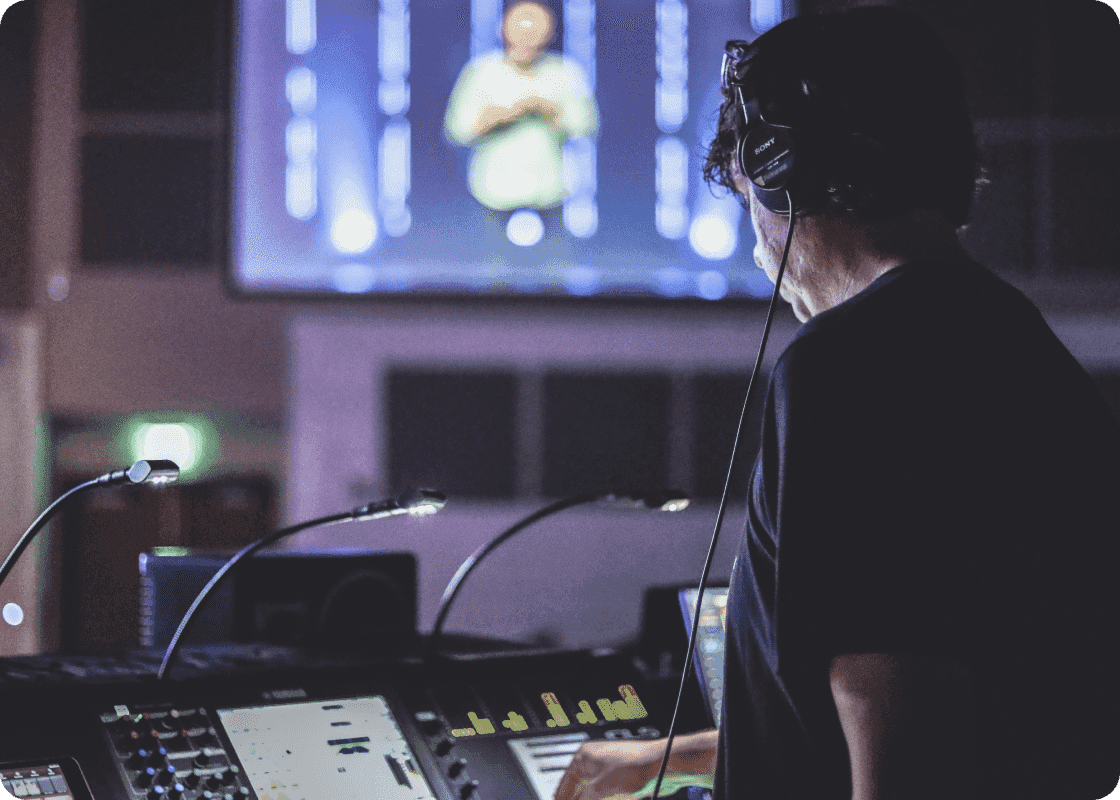 Production operator at a console with stage screens in the background