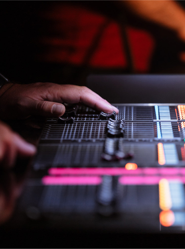 Hands adjusting an audio mixer at a live event, showcasing audio visual solutions.